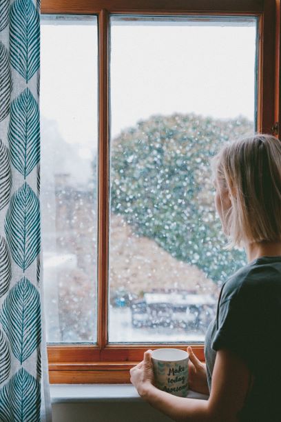 woman-gazing-out-window-into-snow